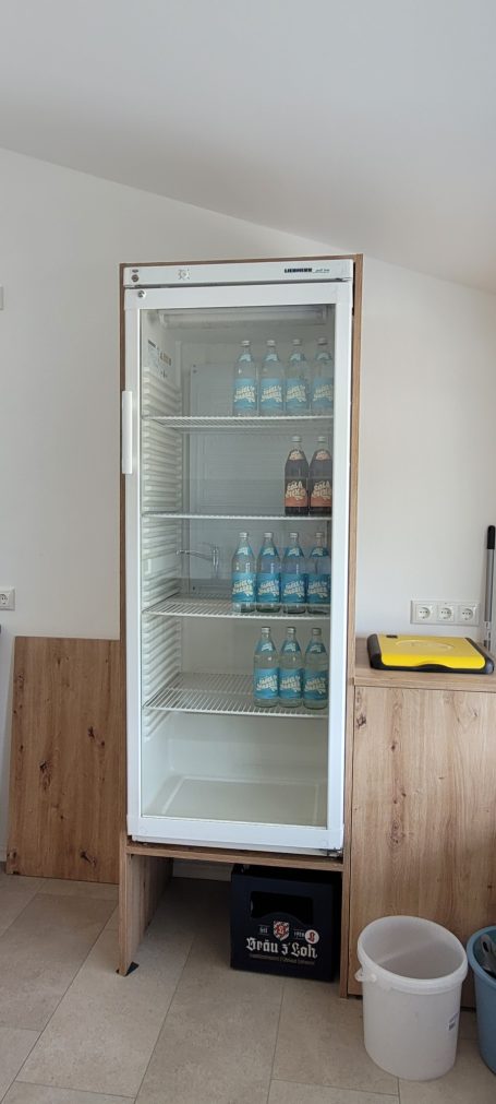 Kühlschrank mit gläserner Tür, leer bis auf einige Flaschen auf den Regalen.