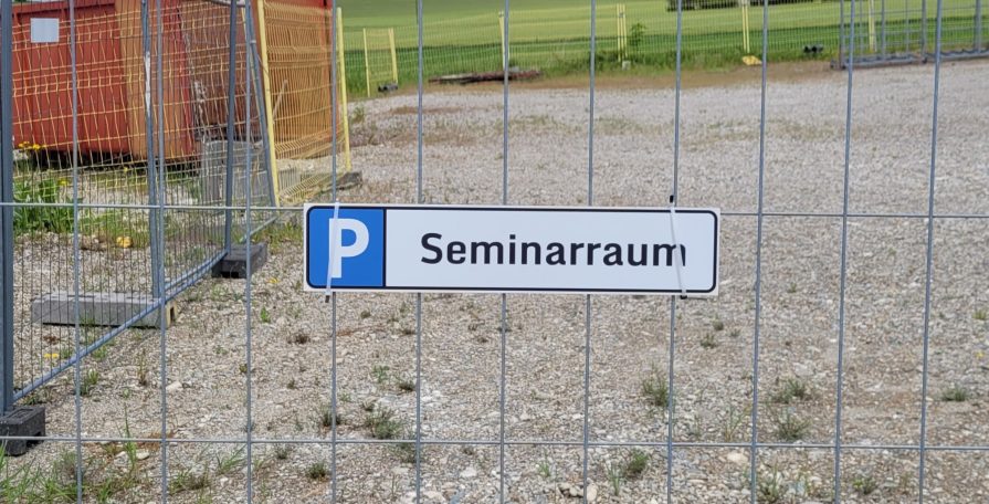 Parkschild für Seminarraum an einem Zaun, mit gelbem Hintergrund.